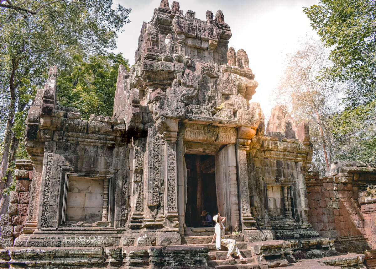 girl sitting in front of temple ruins in Angkor