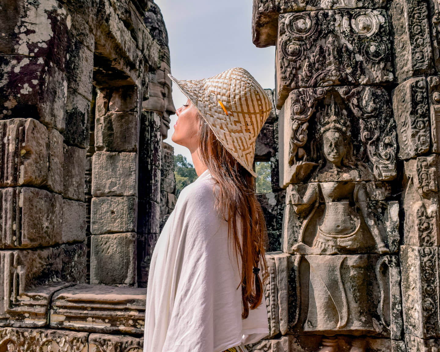 girl pretending to kiss stone face at temple ruins